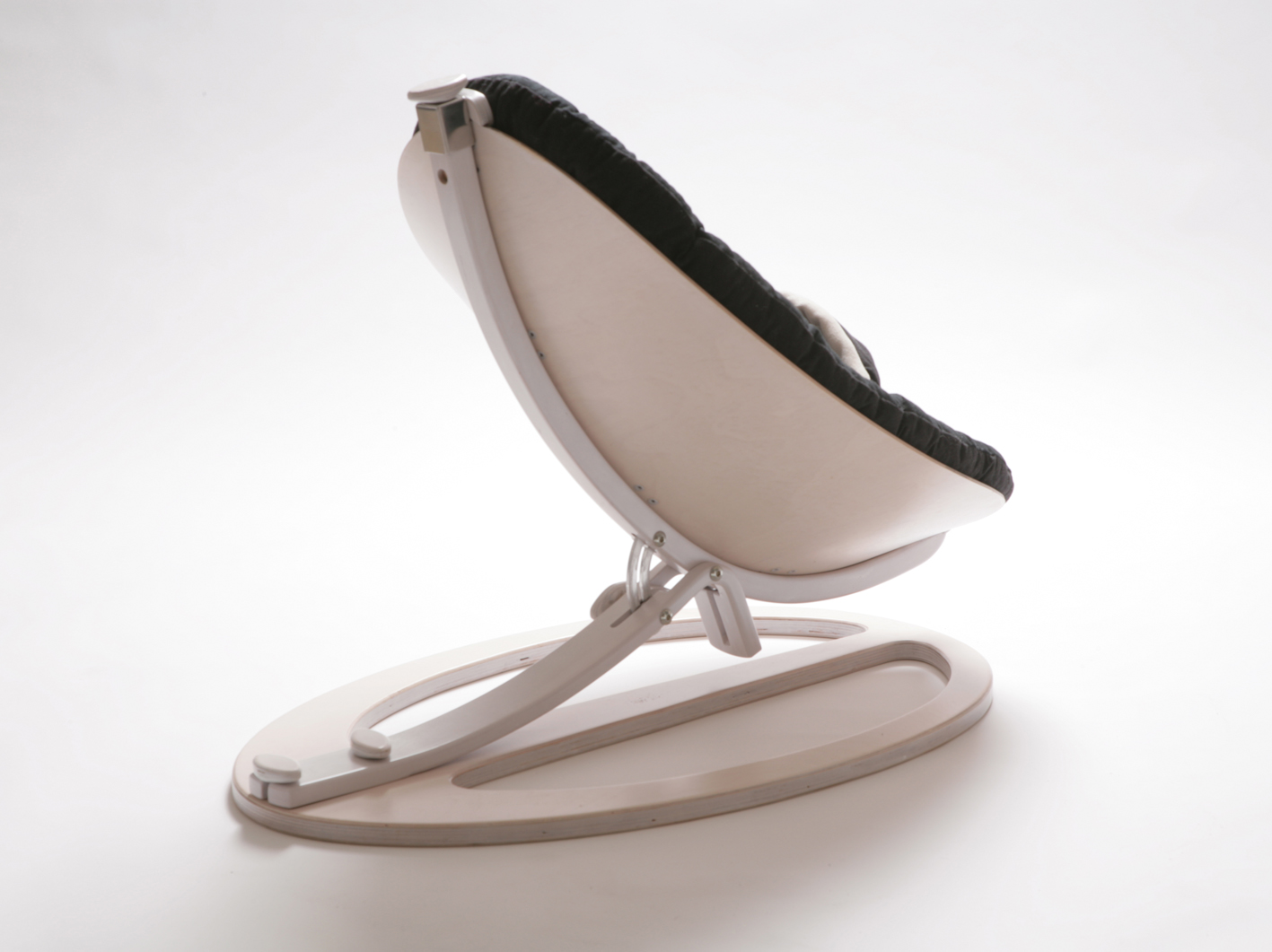A modern white curved lounge chair with dark cushioning on an oval wooden base, plain white background